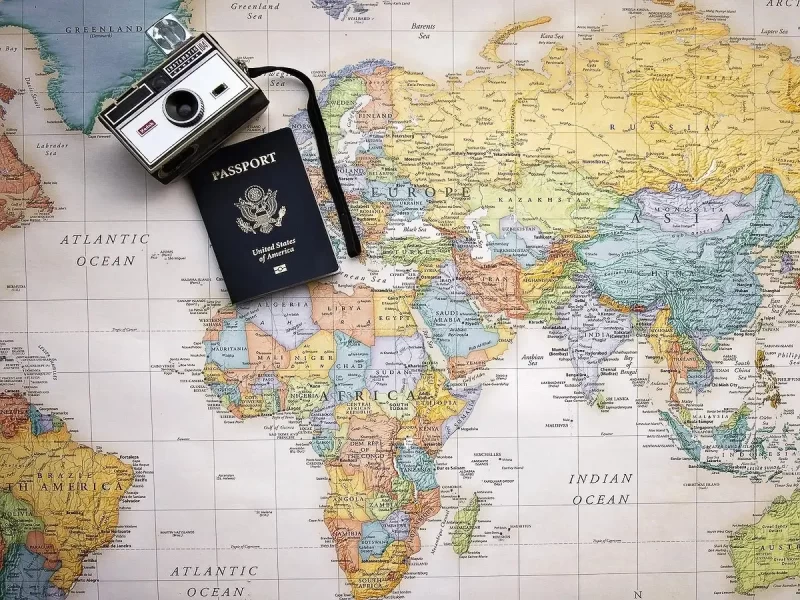 Camera and passport on top of colorful world map