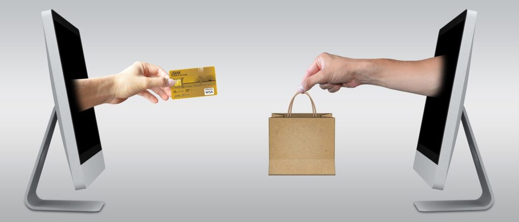 Two hands reaching out of monitors exchanging money for goods