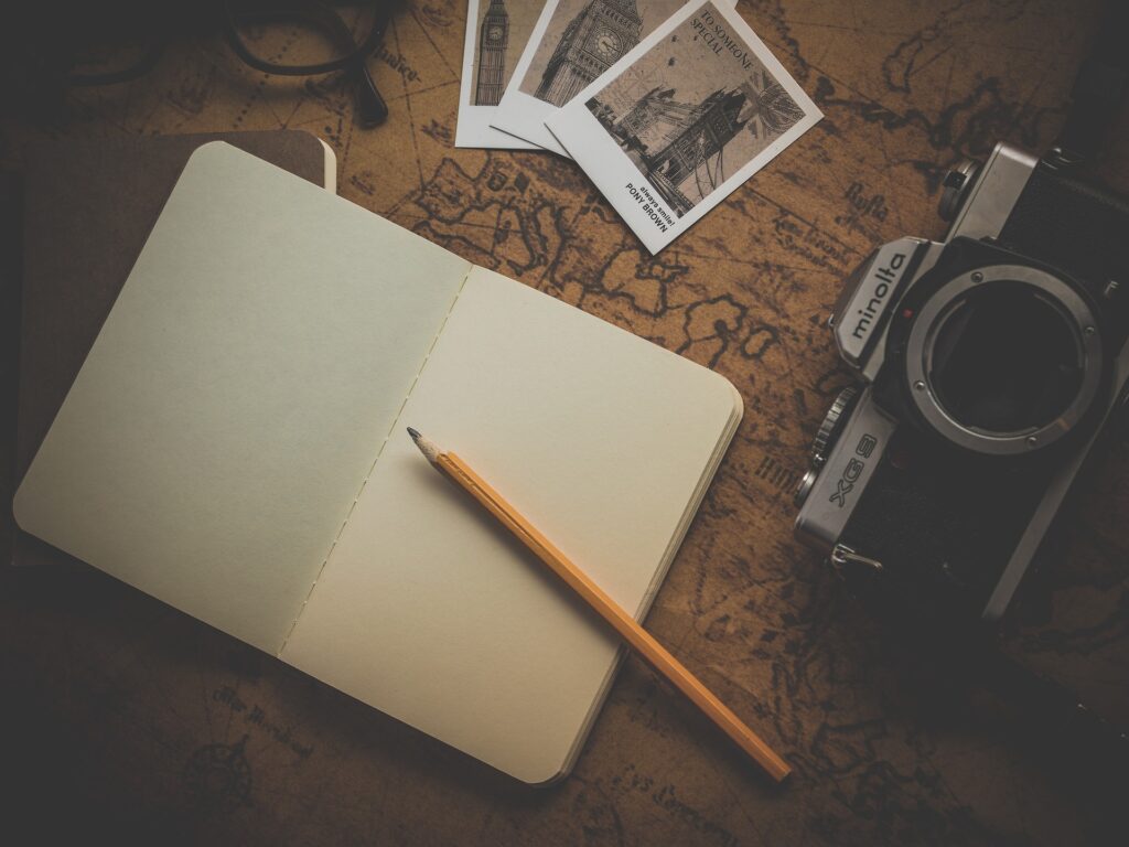 Notebook, pencil, camera and polaroid pictures on a desk