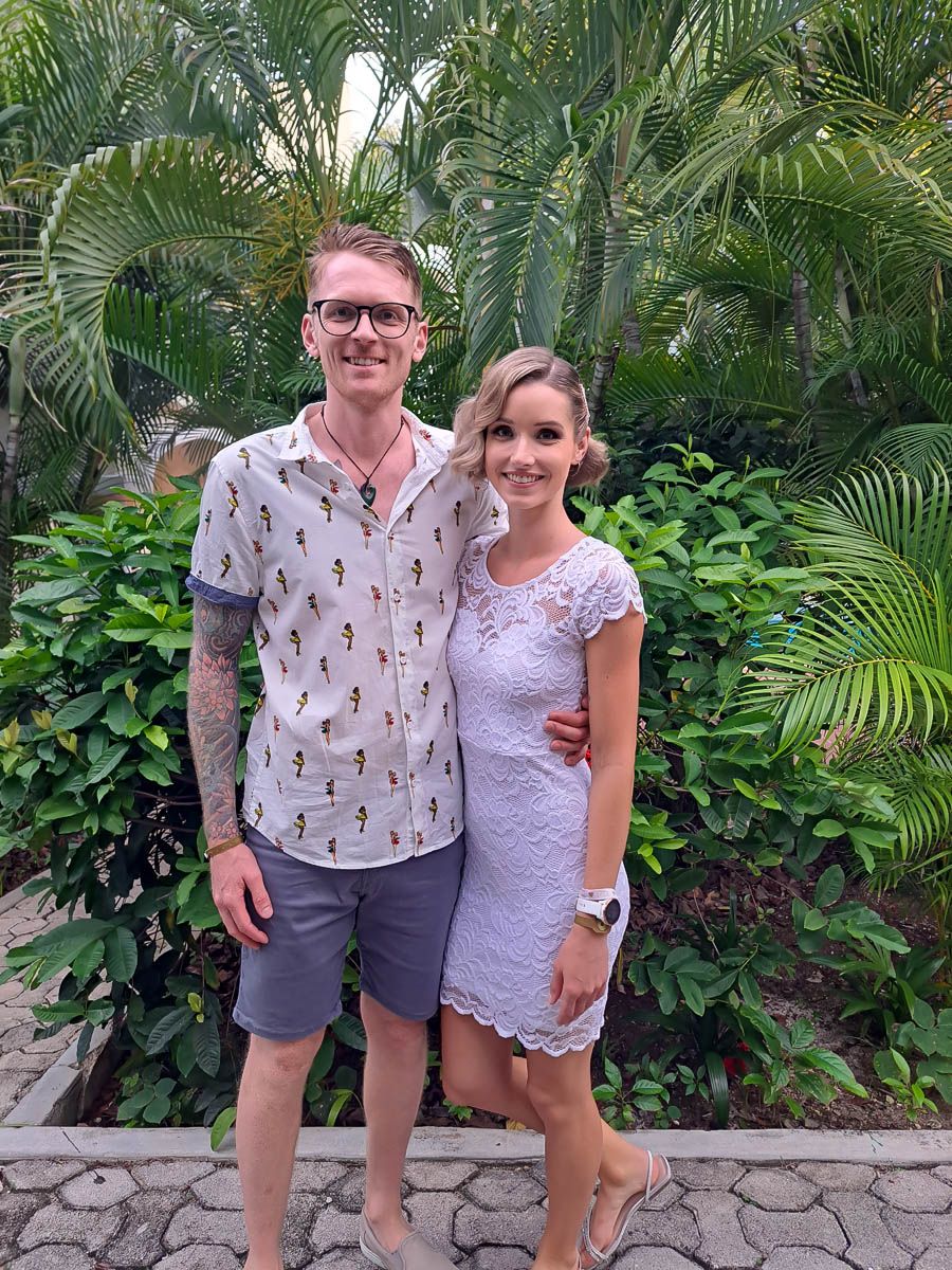 A man and a woman standing in front of tropical trees in Mexico