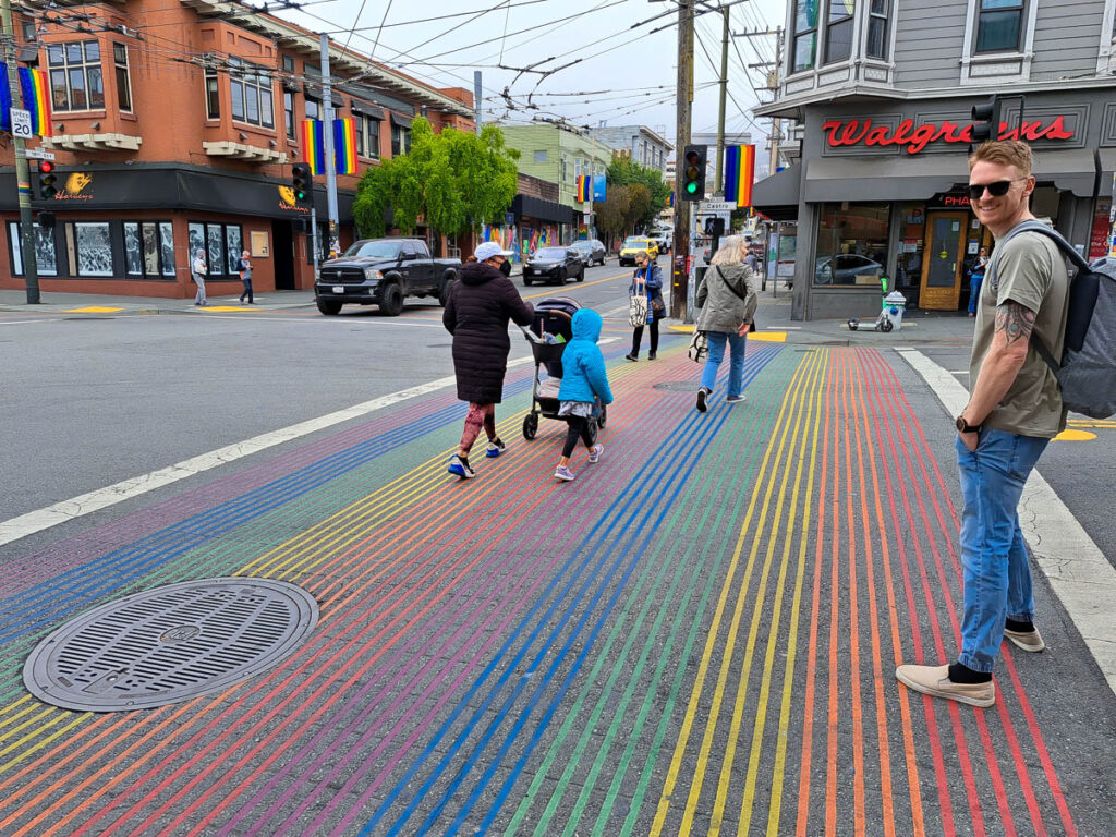 A man walking across a rainbow crosswalk in the Castro District, San Francisco