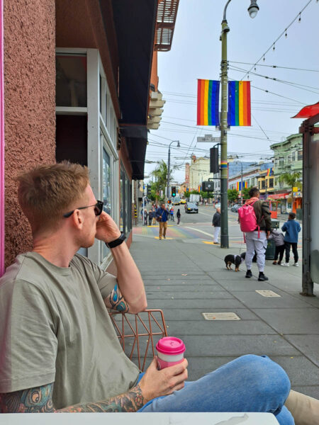 A man sitting outside a coffee shop watching people walking by