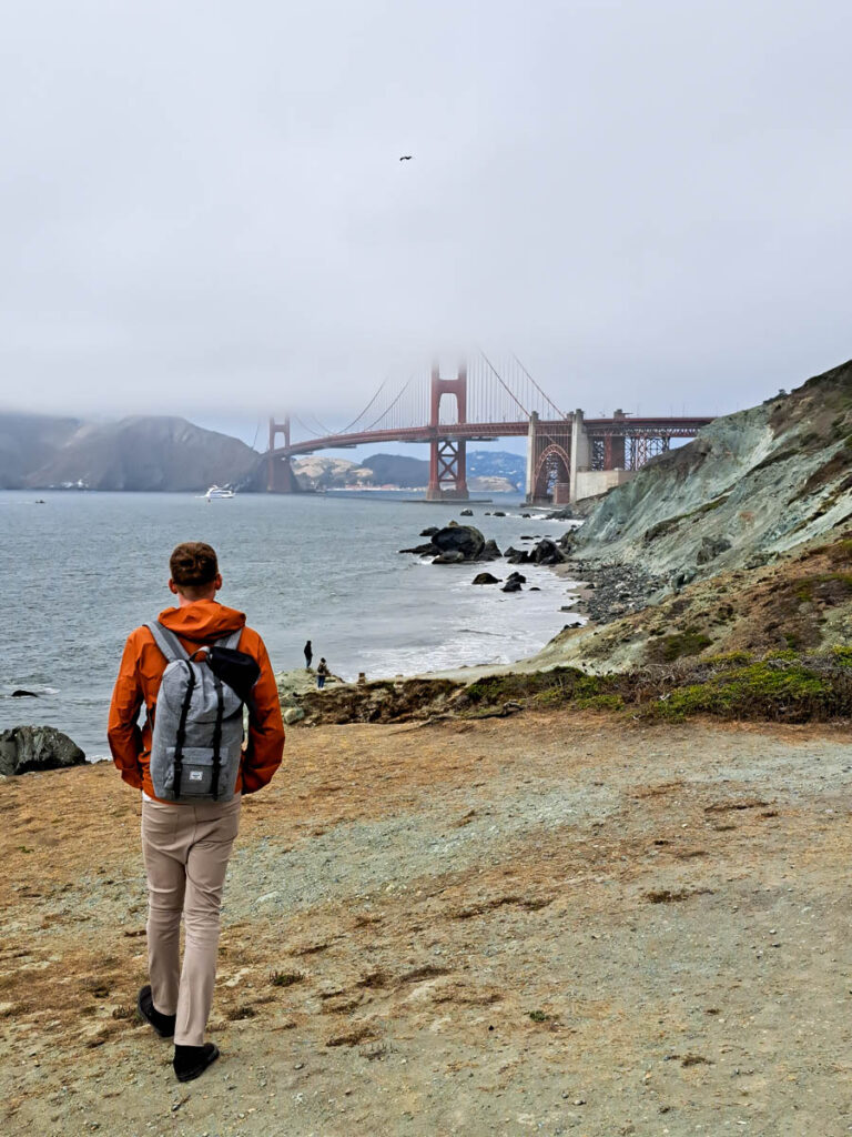 A man looking out at the Golden Gate bridge on a foggy day