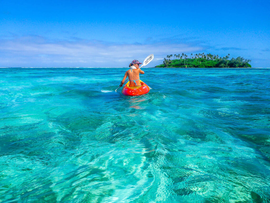 A woman in a kayak floating on clear water in Rarotonga, Cook Islands