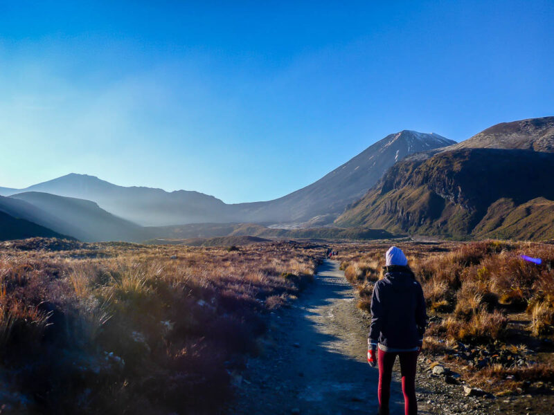 A woman walking through a valley towards a mountain in New Zealand