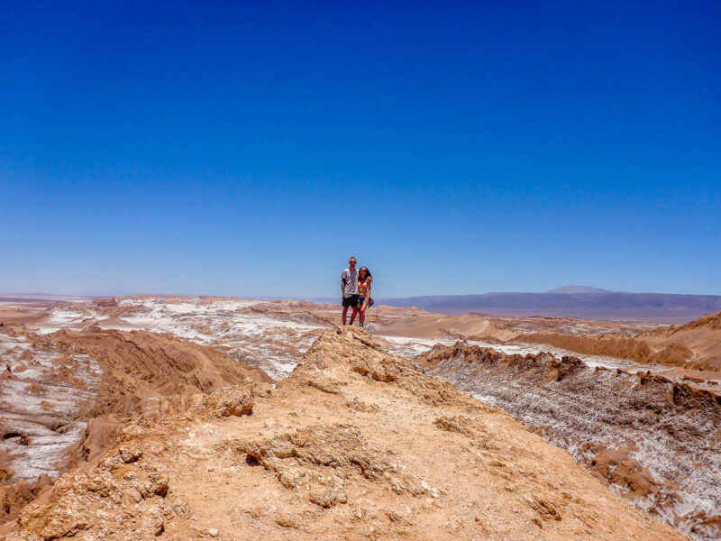 A man and a woman traveling the Atacama Desert, Chile, standing on top of a mountain