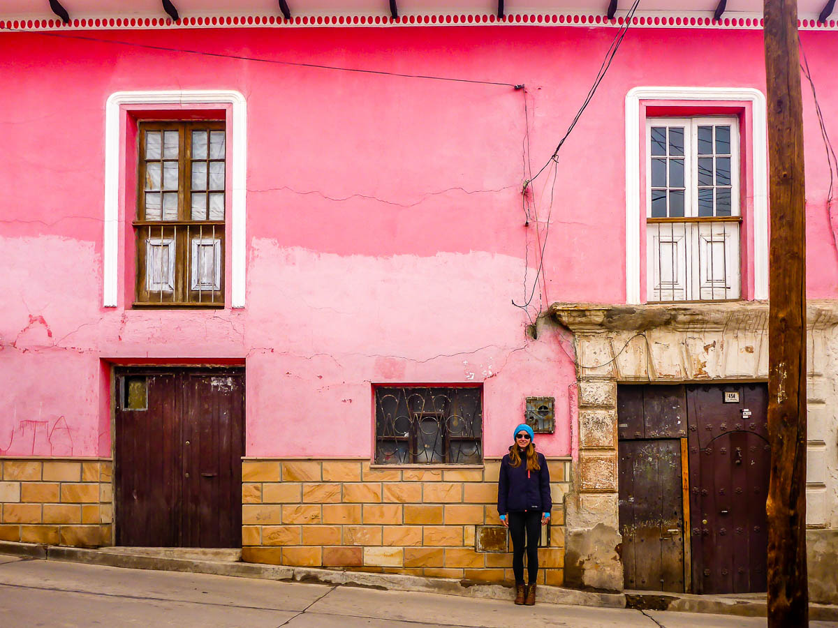 Woman standing in front of bright pink building in Colombia