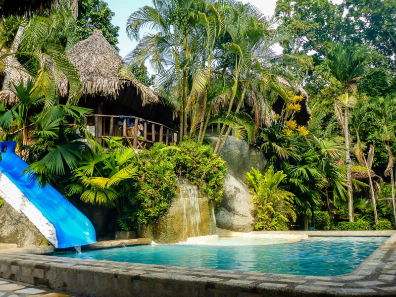 Swimming pool with slide in front of a beach hut set in lush jungle in Tayrona National Park, Colombia