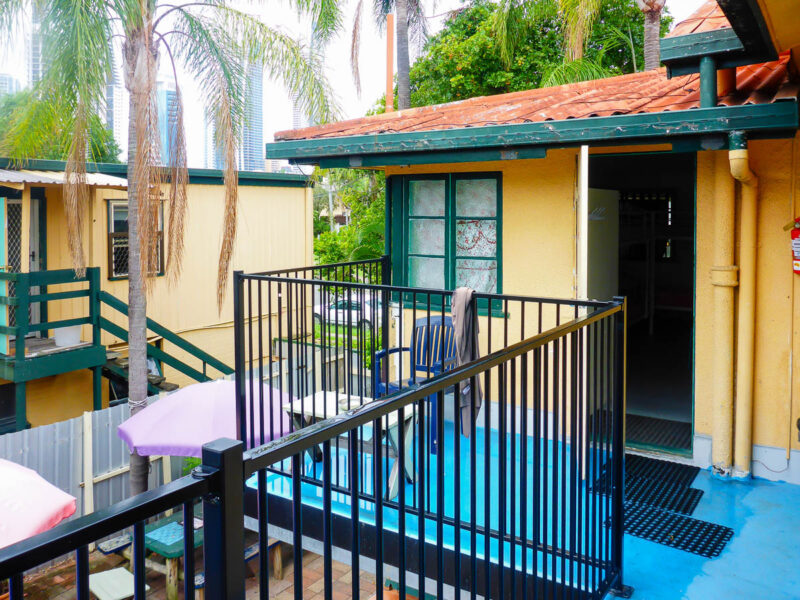 Outdoor balcony and view of a yellow colored hostel with palm trees in Australia