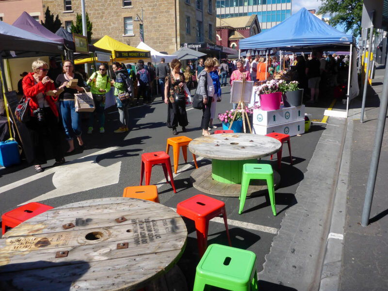 Budget-friendly activity of exploring a market and utilizing the tables and chairs alongside the market stalls in a busy market in Australia