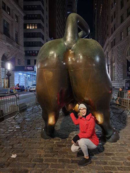  A woman crotched down behind the famous Wall Street Bull in New York City to rub it's balls for good luck