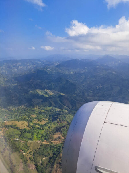 View outside an airport window flying over the mountainous hillside of the Dominican Republic