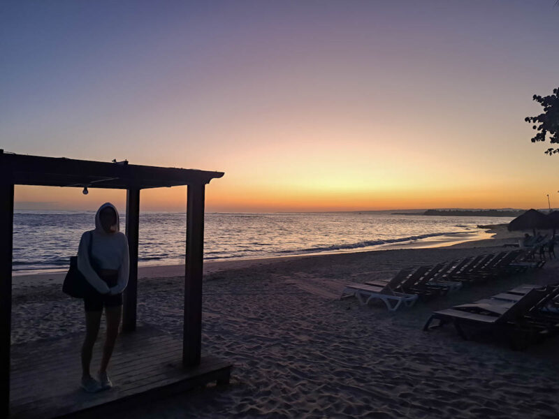 A woman standing in a gazebo watching the sunrise on the beach while on vacation in the Dominican Republic