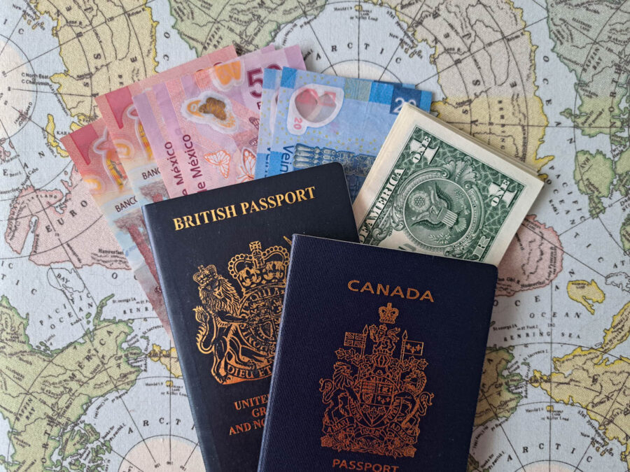 British and Canadian passports on top of mexican pesos and american dollars on a world map background