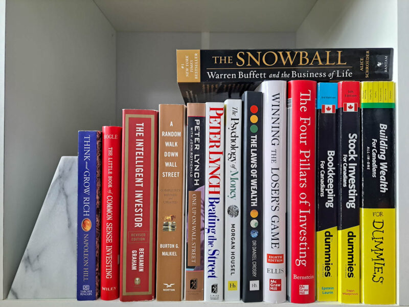 Several finance books lined up on a row including ones on the FIRE movement, Financial Independence Retire Early