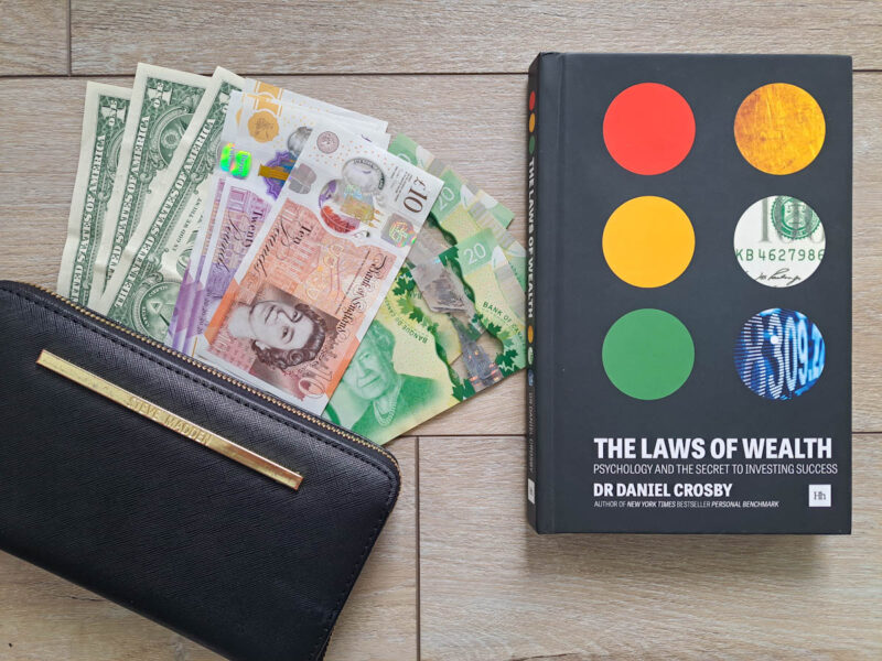 A wallet with american, canadian and english money beside a Financial Independence and investing book