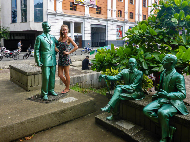 A woman standing with 3 statues in Colombia