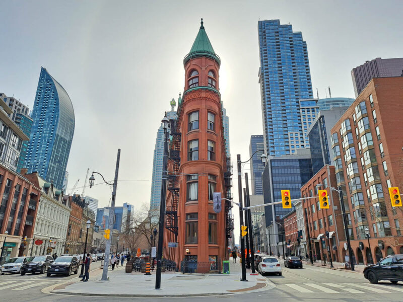 Toronto city streets with tall buildings, street signs, cars, crosswalks and busy city life.