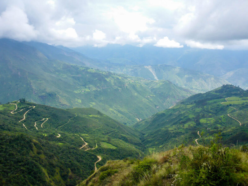 Trails meandering through lush green Andean mountains in Peru.