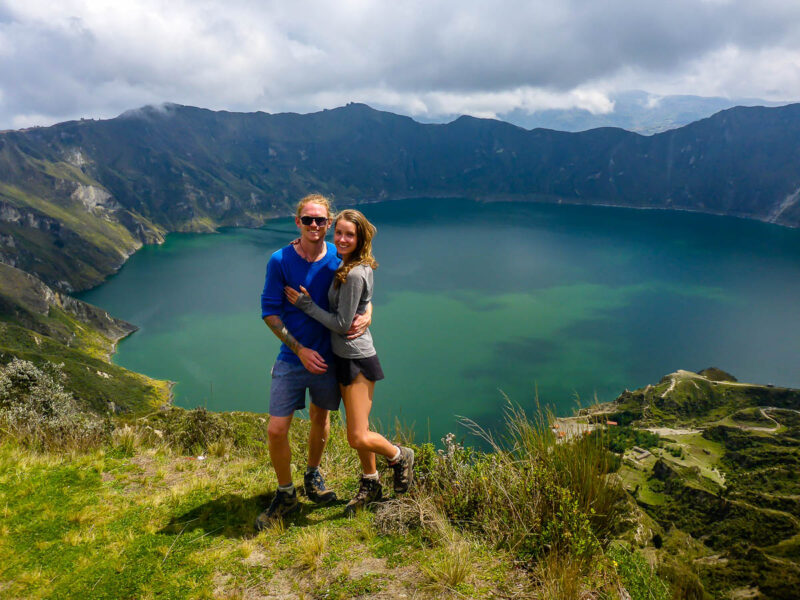 A man and woman standing on a cliff edge overlooking Quilotoa Crater in Ecuador.