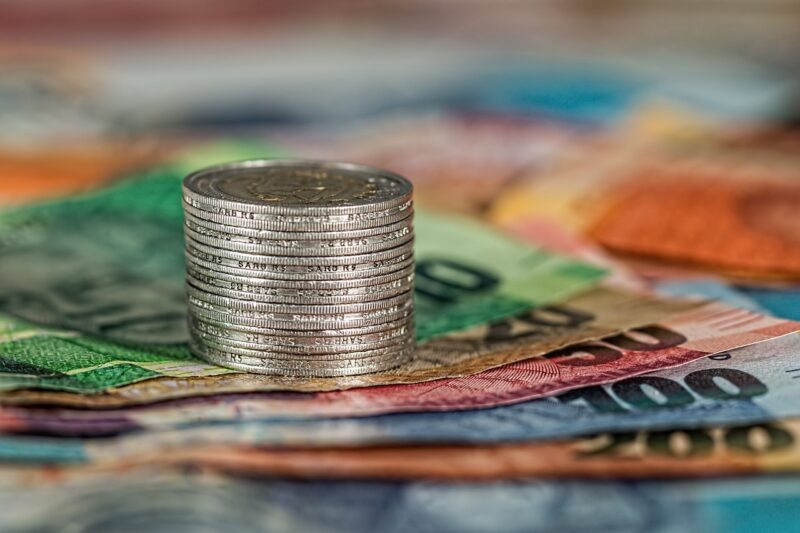 A stack of coins on top of colorful money bills