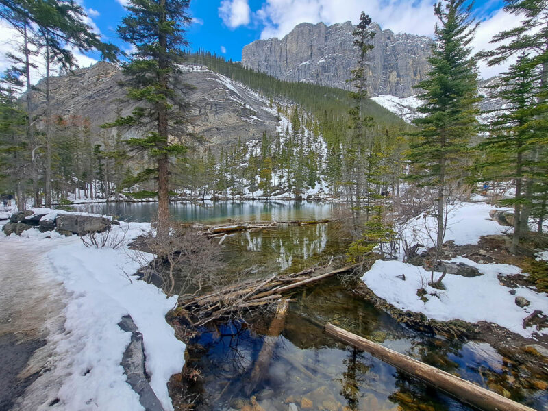 Grassi Lakes in the Rocky Mountains in Canmore, Alberta with high mountain peaks, trees, and snow on the ground