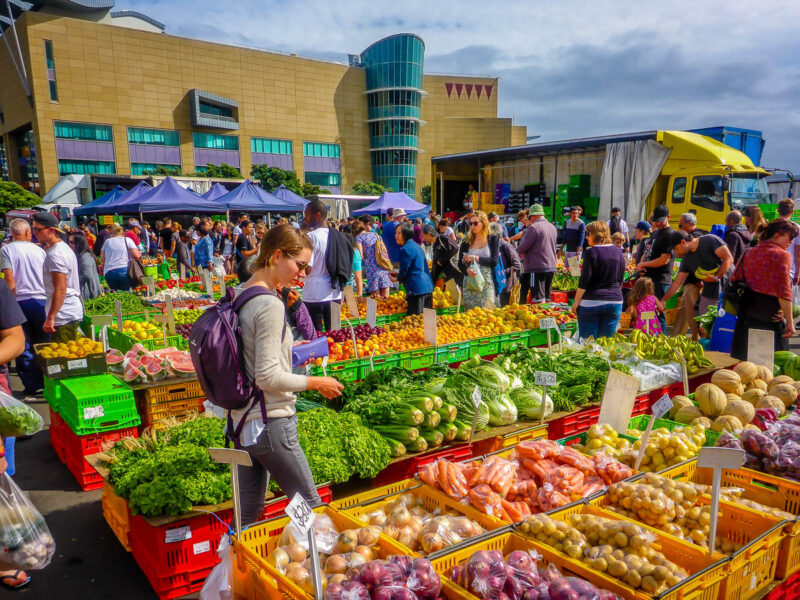 A woman looking at bins of fruit and vegetables at a farmers market