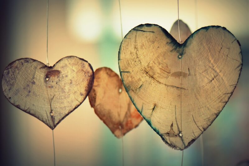 Multiple wooden heart cut-outs hanging by thin wires with a blurred background