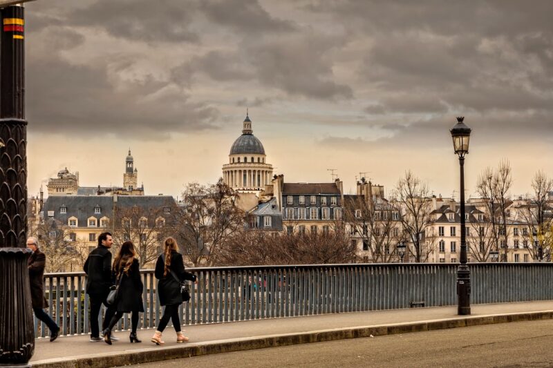 People walking across a bridge in Paris wearing all black