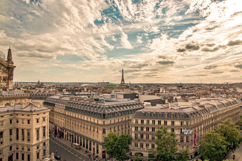 View of Paris from a tall building with the Galeries Lafayette right in front and the Eiffel Tower far in the background, blue skies with wispy clouds