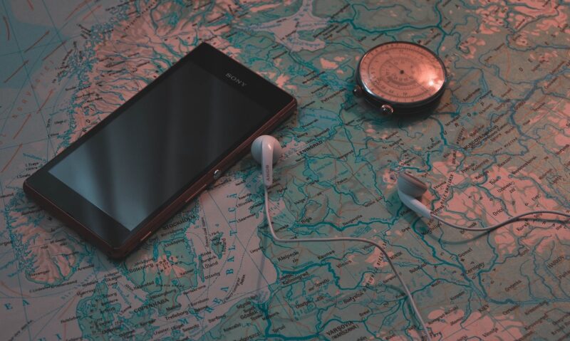 A smartphone, headphones, and compass on top of a map