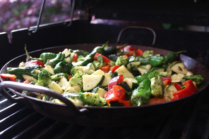 Cast iron frying pan with green and red colored vegetables