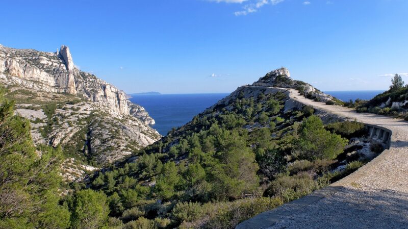 Calanque National Park in Marseille, France with limestone cliffs, green trees and shrubbery, and the Mediterranean Sea