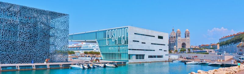 Port of Marseille from the water with Museum of European and Mediterranean Civilizations (MuCEM), La Villa Méditerranée, Basilique Notre Dame de la Garde, small boats, and a cruise ship in the background